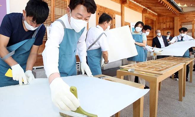 우범기(왼쪽 두 번째) 전주시장이 20일 경복궁 흥복전에서 창호 보수 행사에 참여해 전주 전통한지를 바르고 있다. 전주시 제공