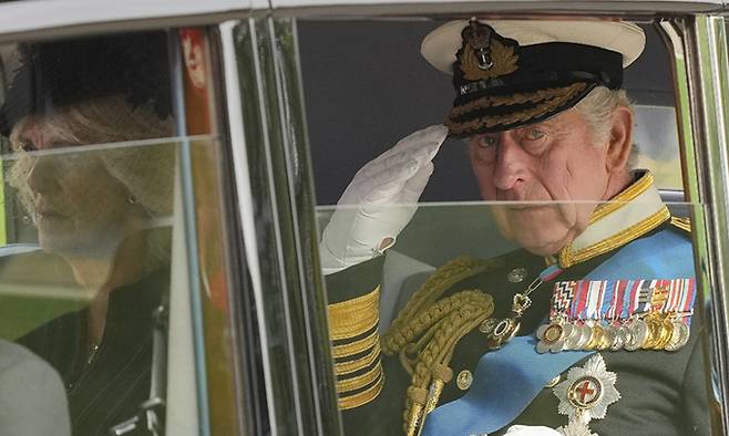 찰스 3세가 19일(현지시간) 커밀라 왕비와 엘리자베스 2세 여왕의 장례식이 열린 웨스트민스터 사원을 차를 타고 빠져나가며 경례를 하고 있다. AP연합뉴스