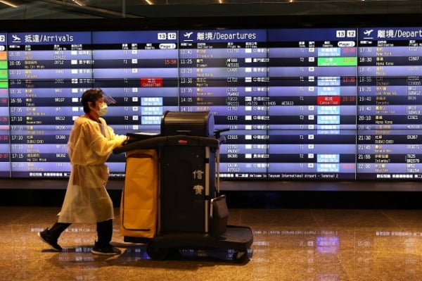 대만 타오위안 국제 공항에서 한 직원이 출발 상황을 보여주는 전광판 앞을 지나가고 있다. /사진=연합뉴스