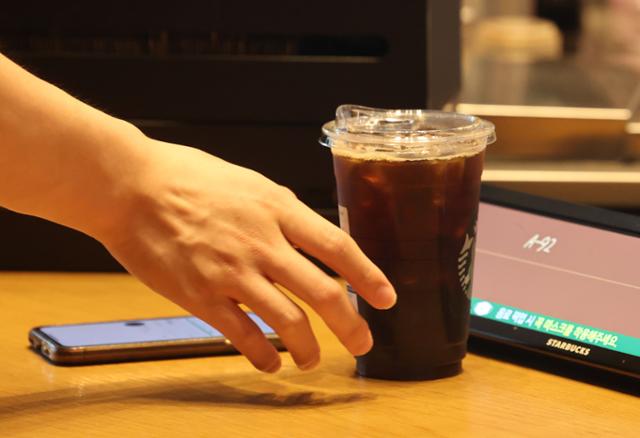 지난 13일 서울의 한 커피전문점에서 시민이 커피를 일회용컵에 담아 가져가고 있다. 연합뉴스