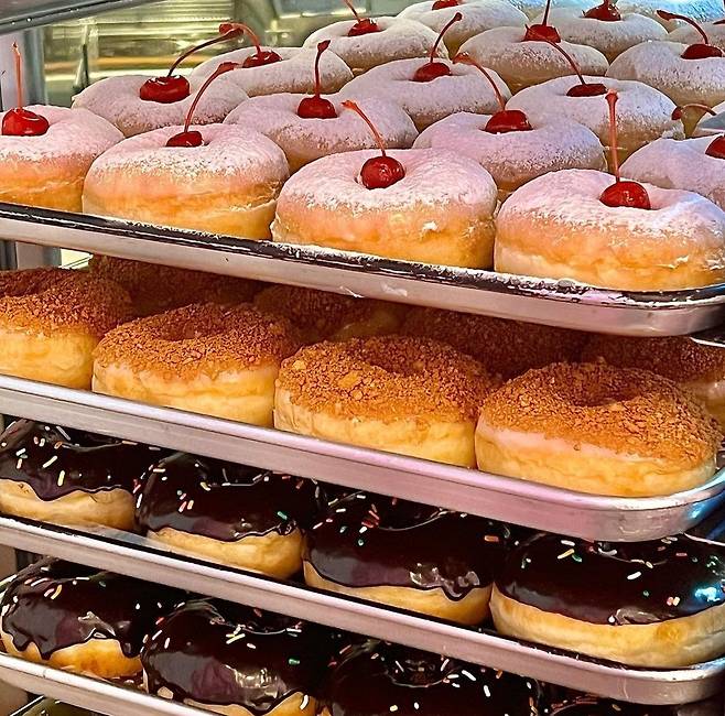 Assorted doughnuts ready to be sold are on trays, at Malddong Donut (Malddong Donut's Instagram)