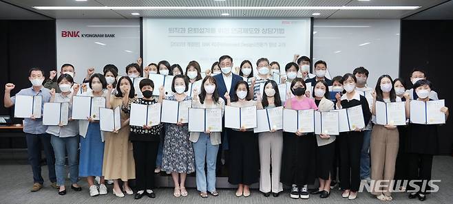 [창원=뉴시스] 홍정명 기자= BNK경남은행 은퇴금융 전문 과정을 지난달 수료한 은퇴디자인 전문가들이 수료증을 들고 기념촬영을 하고 있다.(사진=BNK경남은행 제공) 2022.09.23. photo@newsis.com