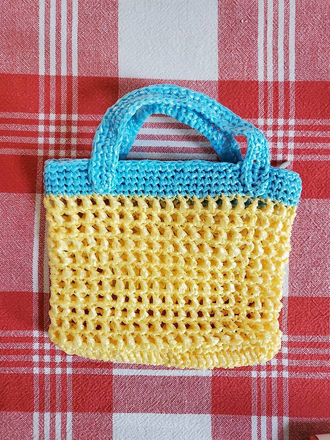 비닐봉지를 실처럼 가늘게 잘라 뜨개질해서 모호연씨가 직접 만든 뜨개 지갑. 간식 파우치로 활용하고 있다. 외국에서는 '플란(Plarn)' 장르로 자리 잡았다. 비닐봉지(plastic bag)를 길게 잘라 뜨개질(yarn)한다는 뜻이다.