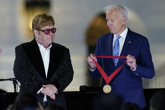 23일(현지시간) 백악관에서 공연한 영국 가수 엘튼 존이 조 바이든 미국 대통령으로부터 훈장을 받고 있다. AP=연합뉴스