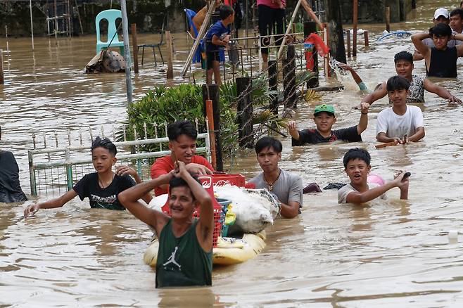 26일(현지시간) 필리핀 북쪽 불라칸주 산미겔에서 주민들이 슈퍼태풍 ‘노루’가 지나가면서 내린 폭우로 가옥이 침수되자 대피하고 있다. EPA=연합뉴스
