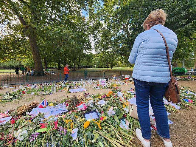 25일(현지시간) 한 시민이 버킹엄궁전 앞 공원에서 영국여왕을 추모하고 있는 모습. 김성우 기자