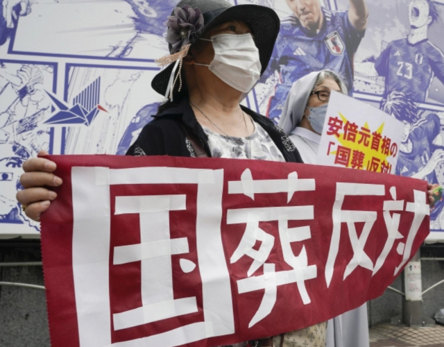 아베 신조 전 총리의 국장에 반대하는 한 일본 시민이 최근 시부야에서 플래카드를 들고 시위하고 있다. 연합뉴스