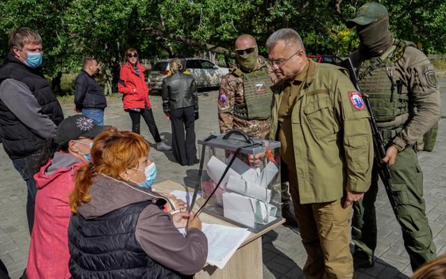 러시아 정부가 임명한 콘스탄틴 이바셴코 마리우폴 시장이 25일 군인들과 함께 지역 투표소를 찾은 모습. 마리우폴=EPA 연합뉴스