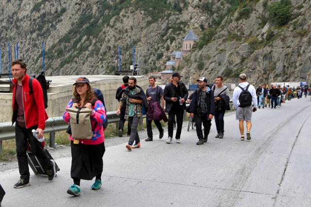 28일(현지시간) 러시아와 조지아 접경 지역인 베르크니 라스에서 국경을 넘은 러시아인들이 걸어서 이동하고 있다. 베르크니 라스=AP 뉴시스