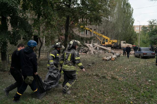28일(현지시간) 우크라이나 미콜라이우카의 한 학교가 러시아군의 공격으로 파괴된 후 실종자 수색 작업을 하던 구조대가 숨진 여성의 시신을 발견해 가방에 넣어 옮기고 있다. 미콜라이우카=AP 뉴시스