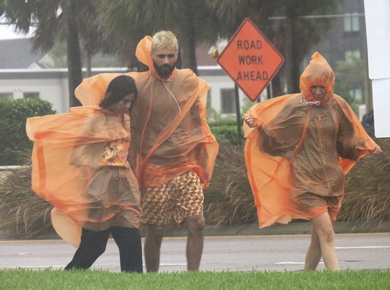 28일(현지시간) 허리케인 이언이 미국 플로리다주에 접근하면서 많은 비를 쏟아붇자 주민들이 우비를 입고 이동하고 있다. AP=연합뉴스