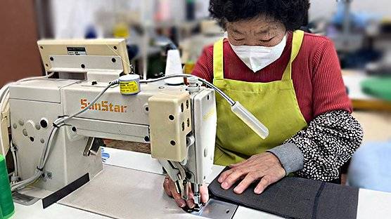 충북 청주 시니어클럽에 소속된 한 어르신이 교복 원단을 재봉틀로 바느질하고 있다. 수명을 다 한 교복은 이 같은 어르신들의 작업과 디자이너의 전문적인 손길을 통해 가방이나 지갑 등 새로운 패션 상품으로 재탄생한다. 사진 SK하이닉스 리버드