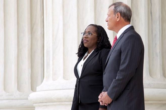 미국 역사상 첫 흑인 여성 연방대법관인 커탄지 브라운 잭슨 대법관(왼쪽)이 30일(현지시간) 공식 서임식을 마친 뒤 존 로버츠 대법원장과 대법원 청사를 배경으로 기념촬영을 하고 있다. 워싱턴=AP연합뉴스