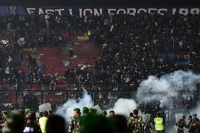1일 폭동이 발생한 인도네시아 자바의 칸주르한 경기장에서 보안요원들 너머로 최루탄 연기가 피어오르고 있다. 자바/AFP 연합뉴스
