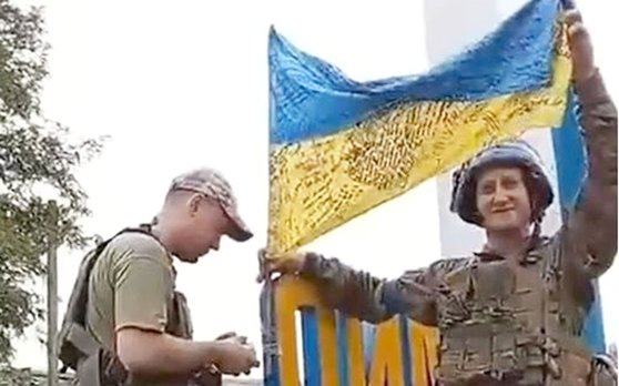 우크라이나 군인 2명이 동부 도시 리만의 표지판에 우크라이나 국기를 설치하면서 환호하고 있다. 사진 우크라이나 대통령비서실장 트위터 캡처