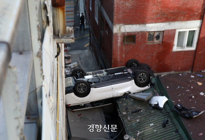 주차장에서 추락한 차량이 인근 건물 지붕에 걸려 뒤집혀 있다. 권도현 기자