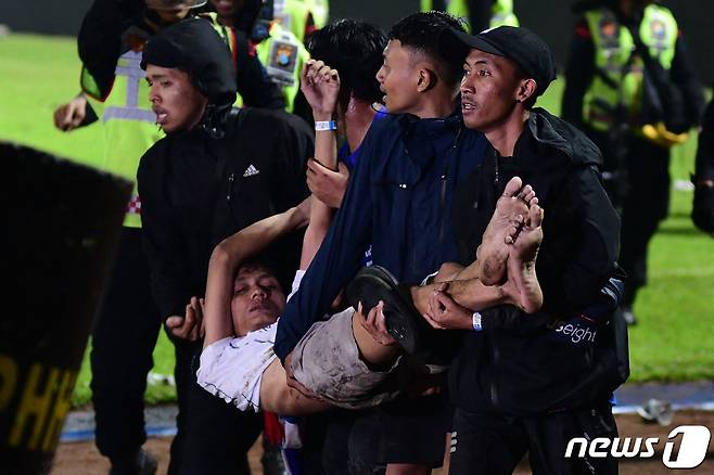 인도네시아 동부 자바 말랑리젠시의 칸주루한 축구장에서 1일(현지시간) 군중들이 쓰러진 남성을 안고 있다. ⓒ AFP=뉴스1 ⓒ News1 김민수 기자