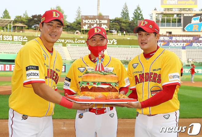 5일 오후 인천 SSG랜더스필드에서 열린 '2022 신한은행 SOL KBO 리그' 롯데-SSG의 경기 전 한유섬과 서진용이 생일을 맞은 김원형 감독에게 대형 햄버거 케이크를 선물하고 있다. (SSG랜더스 제공) 2022.7.5/뉴스1