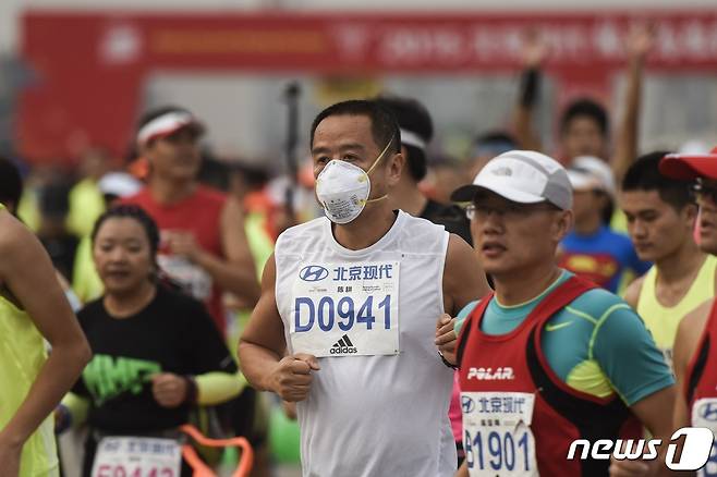 지난 2015년 9월20일 중국 베이징에서 열린 마라톤 대회. 참가자가 스모그 때문에 숨을 쉬기 힘들자 마스크를 착용한 채 달리고 있다. 2015.09.20 ⓒ AFP=뉴스1 ⓒ News1 김예슬 기자