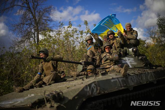 [리만=AP/뉴시스] 우크라이나 군인들이 4일(현지시간) 우크라이나의 이지움과 리만 사이의 도로를 지나는 장갑차 위에 앉아 국기를 들고 있다. 2022.10.05.