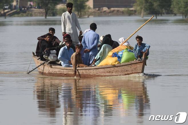 지난달 4일(현지시간) 파키스탄 펀자브 지방 라잔푸르 지역에서 홍수 피해를 입은 주민들이 보트를 타고 이동하고 있다.ⓒ AFP=뉴스1