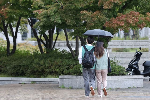 서울 성북구 고려대 안암캠퍼스에서 10일 오후 한 쌍의 남·여가 우산을 함께 쓰고 걸어가고 있다. 연합뉴스