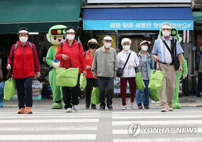 지난 5일 도로교통공단이 경기도 의정부 제일전통시장에서 한국노인종합복지관협회, 의정부노인종합복지관과 함께 진행한 ‘어르신 교통사고 제로 캠페인’ 현장에서 고령 보행자들이 안전 장바구니를 들고 횡단보도를 건너고 있다. ⓒ연합뉴스