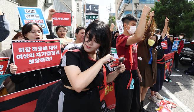 서울 용산구 주한이란대사관 앞에서 지난 5일 열린 집회에서 아이사(앞줄 왼쪽)가 히잡 착용을 강제하는 이란 정부에 저항하는 표시로 자신의 머리카락을 자르고 있다. |연합뉴스