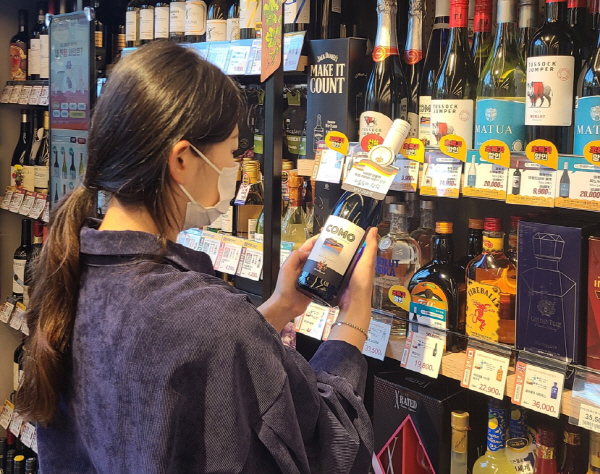 한 소비자가 이마트24 매장에서 꼬모 리슬링 와인 상품을 살펴보고 있다. [사진 제공 = 이마트24]