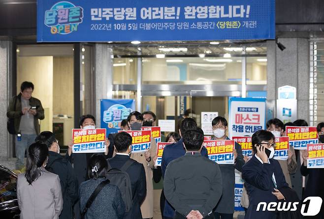 더불어민주당 의원들이 19일 오후 압수수색 중인 서울 여의도 더불어민주당사 앞에서 항의 손 피켓을 들고 있다. 서울중앙지검은 이날 대장동, 위례신도시 개발사업 특혜 의혹 사건과 관련해 민주당사 내 김용 민주연구원 부원장의 사무실 압수수색을 시도했다. 2022.10.19/뉴스1 ⓒ News1 이재명 기자