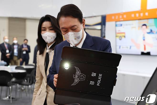 윤석열 대통령이 21일 오전 인천 연수구 송도컨벤시아에서 열린 국제치안산업대전 한국과학기술연구원 부스에서 접이식방검방패를 착용해보고 있다. 왼쪽은 김건희 여사. (대통령실 제공) 2022.10.21/뉴스1 ⓒ News1 안은나 기자