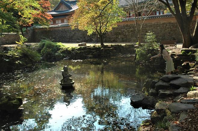 A visitor tosses a coin at the stone Buddhist monk statue at Naejangsa in Jeongeup, North Jeolla Province, Oct. 16. (Lee Si-jin/The Korea Herald)