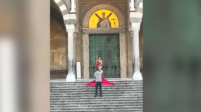 지난 17일 오전 한 여성 관광객이 이탈리아 아말피의 성 안드레아 대성당 앞에서 붉은색 천으로 몸의 일부만 가린채 포즈를 취하고 있는 모습. (사진=아말피노티즈 페이스북)