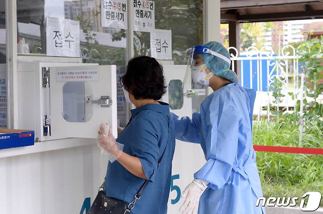 광주 서구 치평동 5·18교육관 주차장에 마련된 임시 선별진료소에서 의료진이 시민에게 코로나19 검사 안내를 하고 있다. 뉴스1 자료사진.