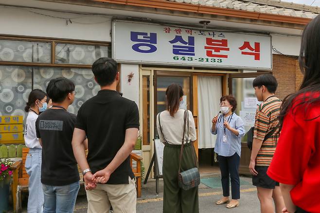 덩실분식 앞에서 해설사가 덩실분식에 대해 설명하고 있다(한국관광공사 제공)