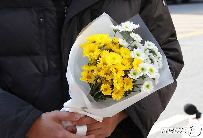 30일 오후 서울 용산구 이태원 압사 사고 현장 인근에 한 시민이 추모를 위해 꽃을 들고 있다. 2022.10.30/뉴스1 ⓒ News1 임세영 기자