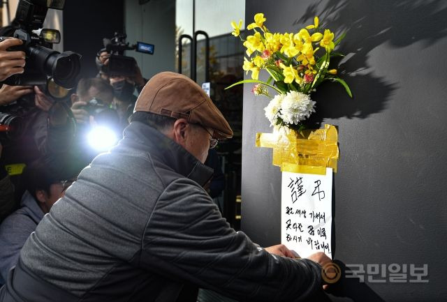 지난 29일 밤 서울 용산구 이태원로 일대에서 대규모 압사 참사가 발생한 가운데 30일 사고 현장을 찾은 시민이 희생자들을 애도하는 조화를 인근 상점 벽에 부착하고 있다.