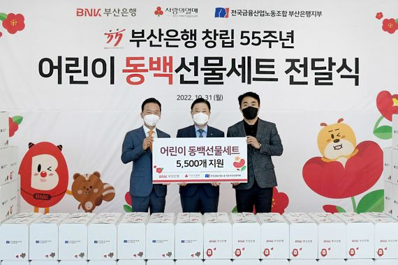 부산사회복지공동모금회 최금식 회장과 부산은행 안감찬 은행장, 부산은행 노동조합 권희원 위원장(왼쪽부터)이 어린이 동백선물세트 전달식에서 기념사진을 찍고 있다./제공=부산은행