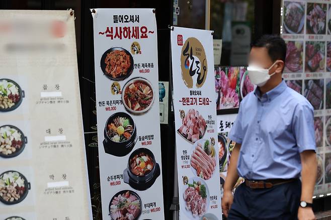 서울 시내 한 거리에서 시민들이 마스크를 착용한 채 식당 메뉴 알림판 앞을 지나고 있다. /뉴스1