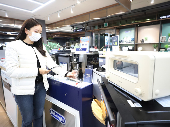 롯데하이마트 대치점을 찾은 소비자가 음식물처리기, 복합오븐, 커피머신 등 인기 주방가전을 살펴보고 있다. [사진=롯데하이마트]