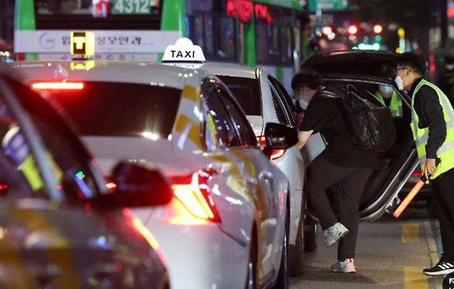 지난 5월 12일 밤 서울 강남역 인근 임시승차대에서 시민이 택시 승차지원단의 도움을 받아 택시를 타고 있다. [사진=연합뉴스]