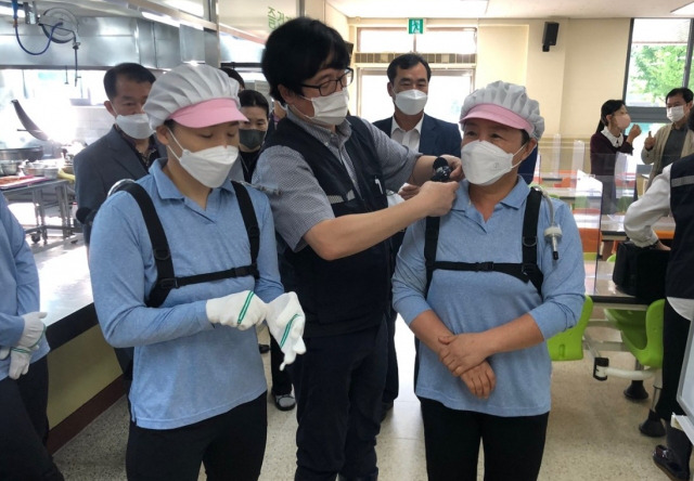 충남도교육청 관계자가 아산의 한 초등학교 급식노동자들에게 배낭형 작업환경 측정기를 착용시키고 있다. 충남도교육청 제공