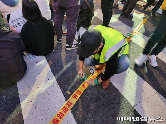 5일 서울 중구 태평로 일대에서 열린 '이태원 참사 희생자 추모 시민 촛불집회'. 한 자원봉사자가 안전 라인을 설치해 보행로를 확보하고 있다./사진=김동규 기자