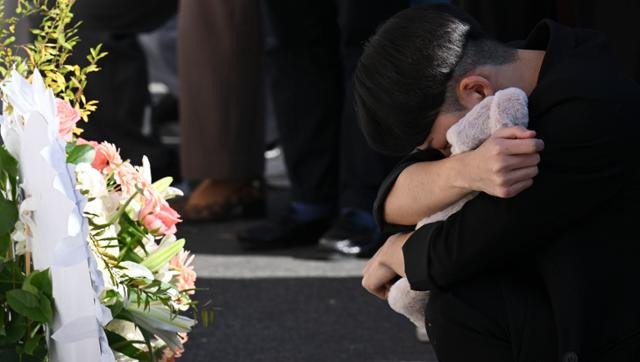 4일 서울 용산구 이태원역 1번 출구 앞 추모 공간에서 이번 참사로 지인을 잃은 A씨가 고인의 유품을 끌어안고 오열하고 있다. 최주연 기자