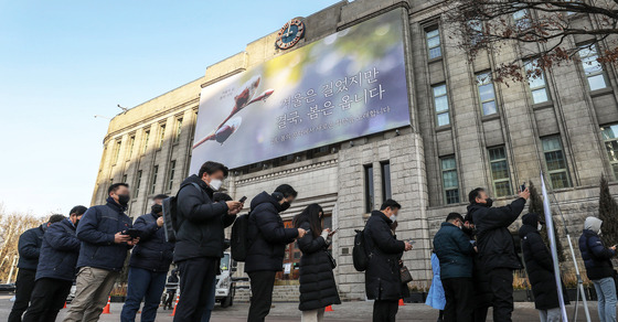 (서울=뉴스1) 민경석 기자 = 7일 오전 서울 중구 서울도서관 벽면에 새단장된 꿈새김판 '겨울은 길었지만 결국, 봄은 옵니다' 아래로 임시 선별검사소를 찾은 시민들이 길게 줄을 서 검사 차례를 기다리고 있다. /뉴스1