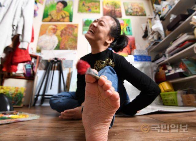 족필화가 이윤정 작가가 지난달 22일 서울 노원구 작업실에서 손대신 발로 붓을 놀리고 있다. 이 작가는 왼발만 간신히 사용하는 최고 단계 중증 장애인이다.