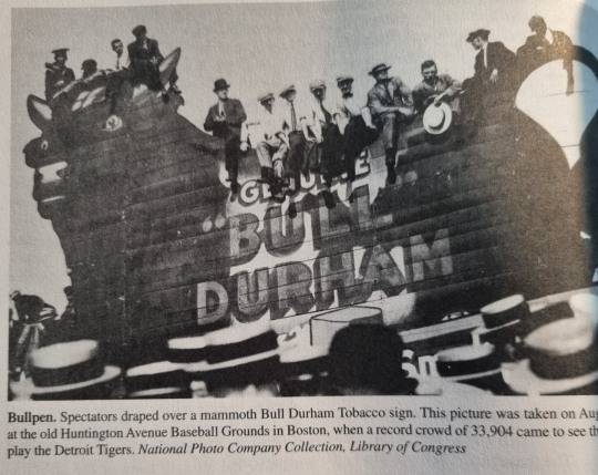 1911년 미국 야구 관중들이 보스턴 허팅턴 에비뉴 경기장에서 담배회사 '불 더햄(Bull Durham)' 광고판위에 앉아 경기를 보는 모습. [폴 딕슨 야구사전 캡처]