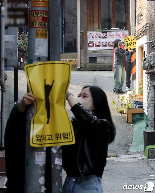 10일 서울 마포구 홍익대 정문 인근 골목에서 시민활동가들이 이제석 광고연구소가 제작한 압사 사고 위험구간 표지판을 시범 부착하고 있다. 2022.11.10/뉴스1 ⓒ News1 장수영 기자