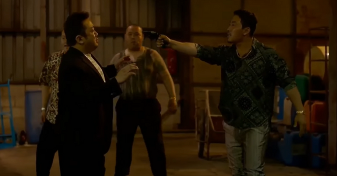 영화 범죄도시2에서 마석도 형사가 한국인 범죄자 라꾸에게 권총으로 위협받고 있는 모습.