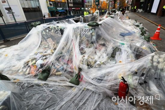 13일 서울 용산구 이태원역 1번 출구 인근에 시민들이 두고 간 국화꽃과 추모 메세지가 대형 비닐로 덮여 있다./윤동주 기자 doso7@